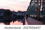 The beautiful little town landscape with the colorful sunset sky and the old iron bridge cross the Delaware river in USA