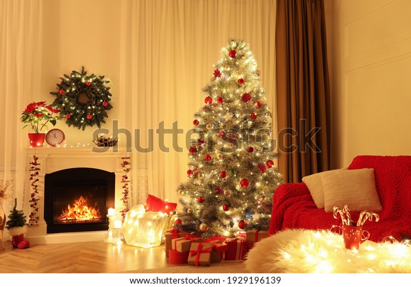 Beautiful living room interior with burning\
fireplace and Christmas tree in\
evening