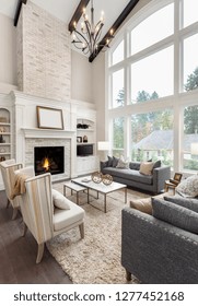 Beautiful Living Room Interior With Hardwood Floors And Fireplace In New Luxury Home. Large Bank Of Windows With Exterior View.