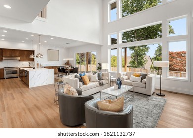 Beautiful Living Room And Kitchen Interior In New Modern Luxury Home With Large Bank Of Windows Showing Exterior View. Features Open Concept Floor Plan, Waterfall Island, Stainless Steel Appliances