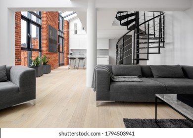 Beautiful Loft Apartment With Exposed Red Brick On The Walls, Big Windows, Stairs And Kitchen Open To Living Room With Modern Gray Furniture