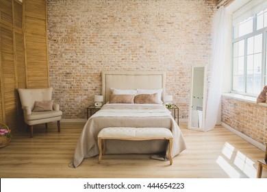 Beautiful loft bedroom with bed near brick wall 