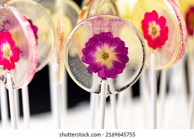 Beautiful lollipop caramel with edible flowers over on dark background