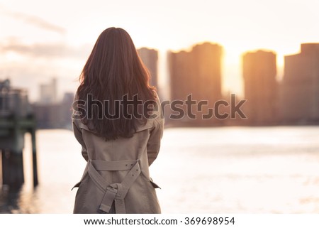 Beautiful lonely girl waiting for somebody bear the water at sunset time