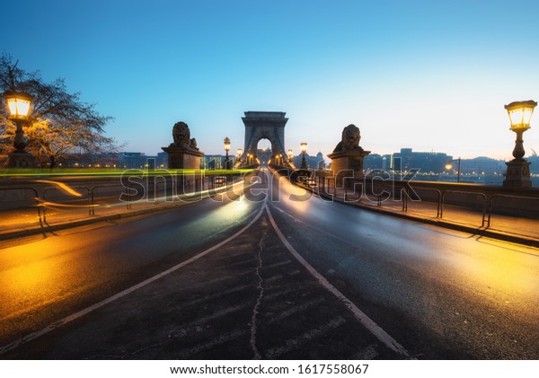 Beautiful\
Long exposure image of Chain Bridge in Budapest, Hungary. View of\
light trails along the road. Dawn\
photography.