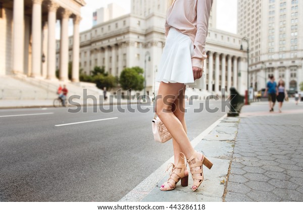美しい長い女性の脚 街の通りに立つ美しい女性で おしゃれな夏の服を着ている ハイヒールの女の子 白いスカート ピンクのtシャツの持ちクラッチバッグ の写真素材 今すぐ編集