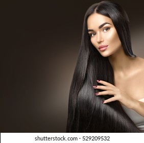 Beautiful long Hair. Beauty woman with luxurious straight black hair on dark background. Beautiful brunette Model girl touching Healthy Hair. Lady with long smooth shiny straight hair. Hairstyle, cure
