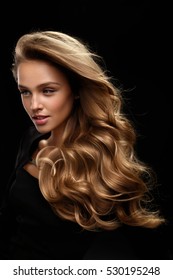 Beautiful Long Hair. Fashion Female Model With Beauty Face Makeup And Healthy Shiny Blonde Wavy Curly Hair On Black Background. Portrait Of Woman With Gorgeous Hairstyle And Hair Color. High Quality