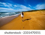 beautiful long hair girl in white shirt walking on a paradise beach in deepwater national park near agnes water, queensland, australia; relax on the tropical beach with red sand	