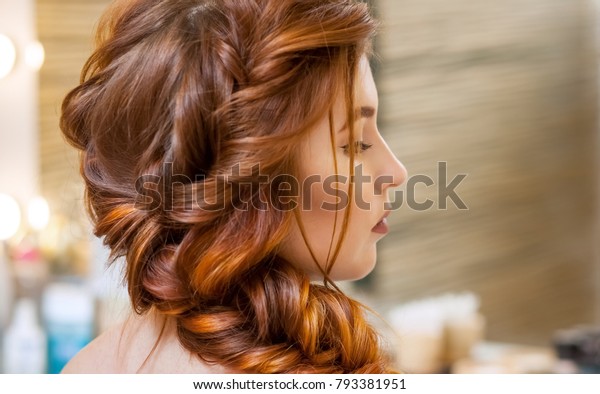 美しく 赤毛の毛の長い女の子を連れ 美容師は 美容室の中にフランスの三つ編みを織り込みます プロのヘアケアとヘアスタイルの作成 の写真素材 今すぐ編集