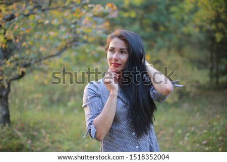 Beautiful long-haired brunette with a playful look and cheerful mood in the autumn park for a walk