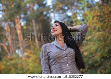 Beautiful long-haired brunette with a playful look and cheerful mood in the autumn park for a walk