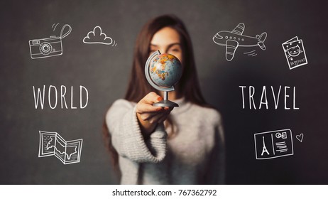 Beautiful long-haired girl is holding small globe on grey background with travel icons, destination chosing concept