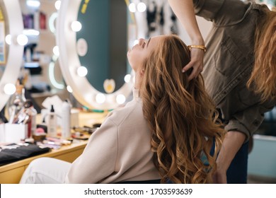 Beautiful lovely blonde woman with long hair sitting at the beauty salon, curling hair