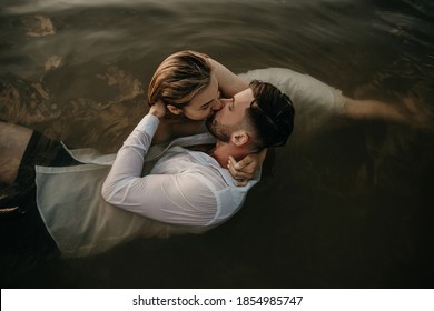 Beautiful loving couple man and woman hug, kiss laying on the water in lake at sunrise. Holidays at sea, sunset, morning, honeymoon, tropics, girlfriend, relationship. Emotional, romantic, creative - Powered by Shutterstock