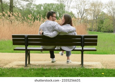 Beautiful loving couple sitting on bench and hugging in park - Powered by Shutterstock