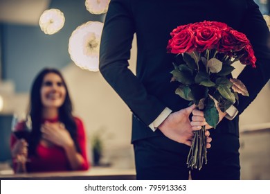 Beautiful loving couple is spending time together in modern restaurant. Attractive young woman in dress and handsome man in suit are having romantic dinner. Celebrating Saint Valentine's Day. - Shutterstock ID 795913363
