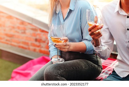 Beautiful Loving Couple Wrapped In One Blanket Smiling At Camera, Young Man And Woman Holding Glasses Of White Wine While Enjoying Time Together At Friends Wedding Outside On Summer Evening