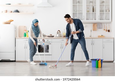 Beautiful loving muslim young couple cleaning floor in kitchen together, full length photo, copy space. Romantic cheerful lady in hijab and her smiling boyfriend house-keeping their new house - Powered by Shutterstock