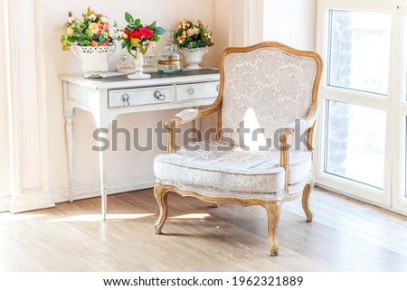 Beautiful luxury classic white bright clean interior bedroom in baroque style with large window, armchair and flower composition