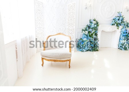 Beautiful luxury classic white bright clean interior bedroom in baroque style with large window, armchair and flower composition