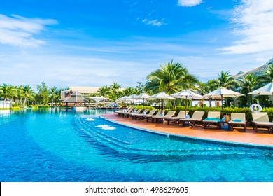 Beautiful Luxury Umbrella And Chair Around Outdoor Swimming Pool In Hotel And Resort With Coconut Palm Tree On Blue Sky - Boost Up Color Processing