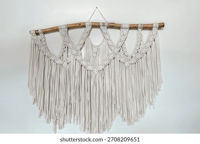 A beautiful macrame wall hanging featuring intricate patterns and long fringes. It is displayed against a clean white background adding a bohemian touch to the decor of a cozy living space.