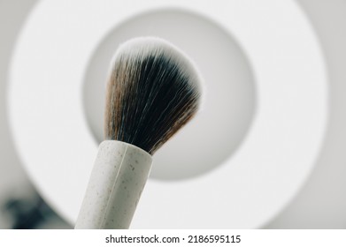 A Beautiful Makeup Brush Made Of Wheat Fibers In Front Of A Ring Light. Makeup Artists, Influencers, And Celebrity Makeup Concept. 