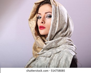 Beautiful makeup woman with red lipstick posing with head covered orient traditional shawl in studio