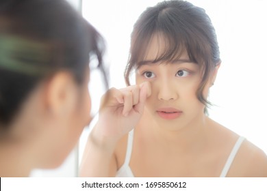 Beautiful and makeup young asian woman looking mirror aging on face and touch eye, beauty asia girl of skincare cosmetic for anti acne wrinkle, healthy care and wellness concept.