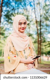 Beautiful Malay Girl Holding Mobile Phone Outdoor Looking At The Watch