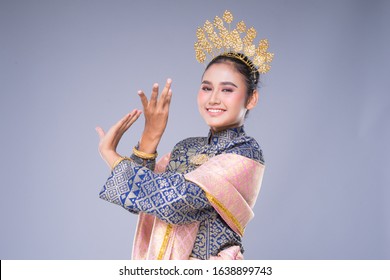 A beautiful Malaysian traditional female dancer with a charming smile performing a cultural dance steps in a traditional outfit. Half length isolated in grey.