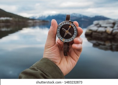 Beautiful male hand holds a magnetic compass against the background of the mountain and a lake. The concept of finding yourself the way and the truth. - Shutterstock ID 1483232873