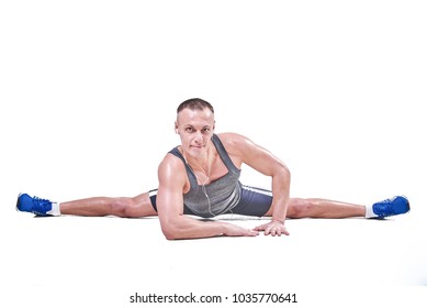 Beautiful man performs side splits in sportswear isolated on a white background 