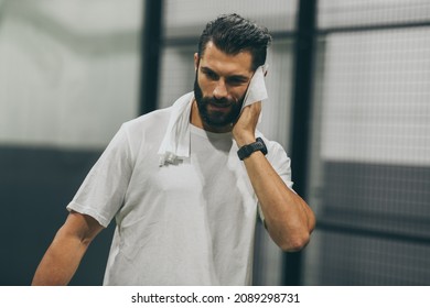 Beautiful man playing paddle tennis, racket in hand wipes the sweat. Young sporty boy at the end of the match. Sweaty padel athlete ready to take shower. Sport, health, youth and leisure concept - Powered by Shutterstock