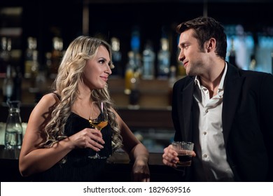 beautiful man and woman at the bar drinking cocktails.