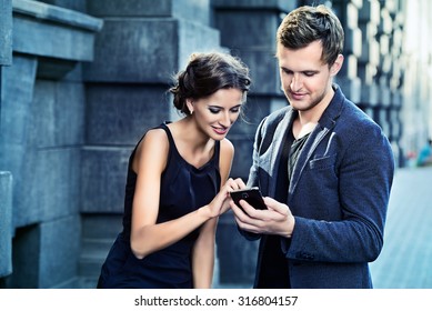 Beautiful Man And Woman Walking On The Street And Making Selfie By Smart Phone. Fashion.