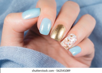 Beautiful manicure. Nail polish being applied to hand, polish is a blue color. Blue background closeup.