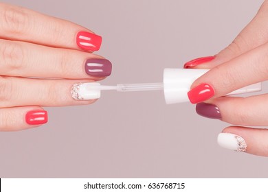 Beautiful Manicure Process. Nail Polish Being Applied To Hand, Polish Is A Top Coat Isolated Grey Red Background Closeup.