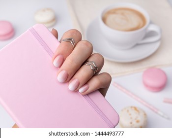 Beautiful manicured hand holding notepad at the office table  Ombre gradient nail design 