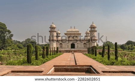 Beautiful marble tomb of Itmad-Ud-Daulah  against the blue sky. Symmetrical mausoleum with domes, minarets, arches. There are ornaments on the walls, inlaid with precious stones. India. Agra