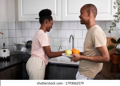 beautiful married couple is preparing breakfast, friendly black man and woman having fun in kitchen, wash fruits together - Powered by Shutterstock