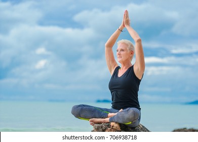 Beautiful Mature Aged Woman Doing Yoga On A Desert Tropical Beach.