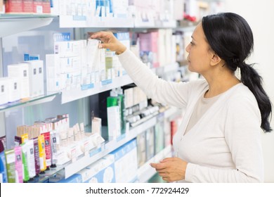 Beautiful Mature Asian Woman Choosing Cosmetics At The Drugstore Reaching For Something On A Shelf Copyspace Pharmacy Buyer Shopping Shop Store Consumer Customer Purchase Beauty Lifestyle