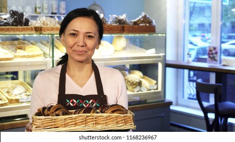 Beautiful Mature Asian Woman Smiling Joyfully To The Camera Holding A Basket With Freshly Baked Delicious Chocolate Croissants Posing At Her Bakery Business Owner Baker Profession Sales.