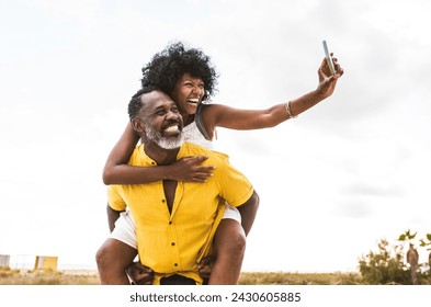 Beautiful mature black couple of lovers dating at the seaside - Married african middle-aged couple bonding and having fun outdoors, concepts about relationship, lifestyle and quality of life - Powered by Shutterstock