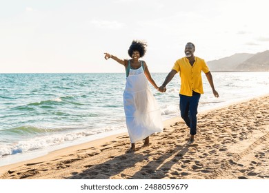 Beautiful mature black couple of lovers dating at the seaside - Married african middle-aged couple bonding and having fun outdoors, concepts about relationship, lifestyle and quality of life - Powered by Shutterstock