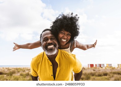 Beautiful mature black couple of lovers dating at the seaside - Married african middle-aged couple bonding and having fun outdoors, concepts about relationship, lifestyle and quality of life - Powered by Shutterstock