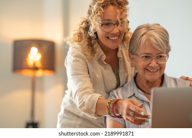 Beautiful mature blonde woman teaching her mother how to use laptop browsing on internet - Shutterstock ID 2189991871