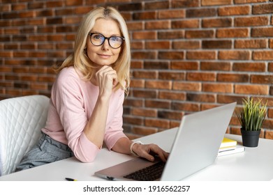 Beautiful Mature Businesswoman Working With Laptop,looking At The Camera, Smiling And Typing, Interrupted From Work,best Worker,workoholic,beautiful Neat Middle-aged Woman,working At The Modern Office